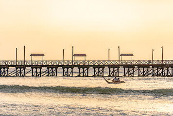 Fototapeta na wymiar fisherman on the beach under a sunset next to a pier