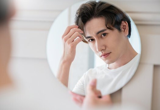 Closeup portrait of handsome beautiful asian boy mirror makeup routine with copy space. Beauty influencer guy with perfect glow skin dress up. Healthcare man lifestyle cosmetic blogger hair concept