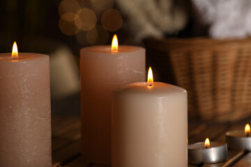 Spa composition with burning candles on wooden table, closeup. Space for text