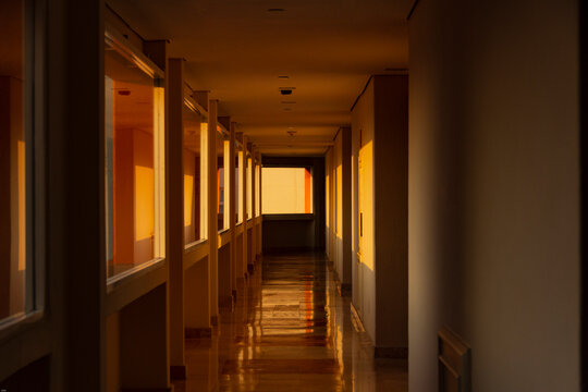 Perspectiva de un corredor moderno con fuertes contrastes de luz y sombras geom&eacute;tricas al atardecer
