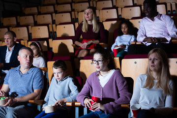 Spectators eating popcorn and watching a movie at the cinema