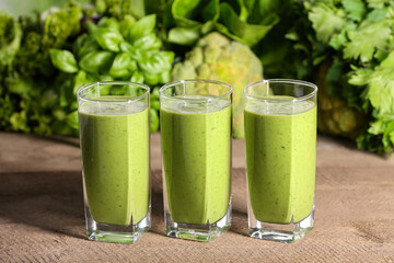 Glasses of fresh green smoothie and ingredients on wooden table