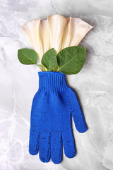 Gardening gloves with beautiful flowers on light grey marble table, top view