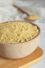 Bowl of aromatic mustard powder on white wooden table, closeup