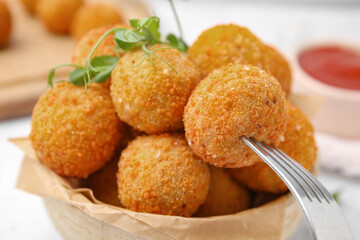 Taking delicious fried tofu ball with fork from bowl, closeup