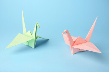 Origami art. Colorful handmade paper cranes on light blue background