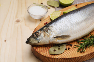 Delicious salted herring, bay leaves, lime, rosemary and salt on wooden table, closeup