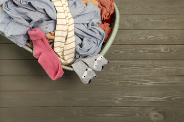 Laundry basket with clothes on dark grey wooden floor, top view. Space for text