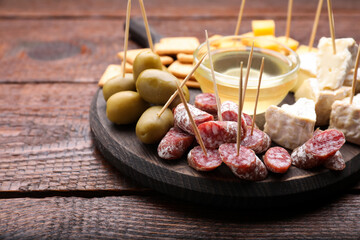 Toothpick appetizers. Pieces of sausage, cheese and honey on wooden table, space for text
