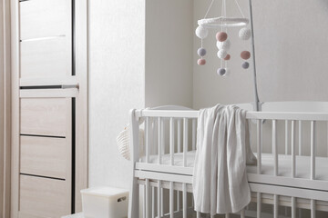 Modern crib with baby mobile in children's room. Interior design