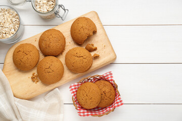 Delicious oatmeal cookies and flakes on white wooden table, flat lay. Space for text