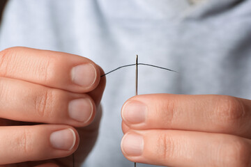 Closeup view of woman threading sewing needle