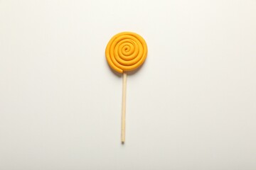 Yellow lollipop made of plasticine on white background, top view