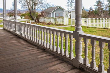 Wooden walkout deck with white railings outdoor in a beautiful garden. Wooden deck of a house with white railings