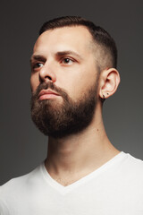 Obraz premium Male beauty concept. Portrait of proud charismatic active 30-year-old man posing over dark gray background. Perfect haircut. Hipster style. Close up. Studio shot
