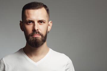 Male beauty concept. Portrait of proud charismatic active 30-year-old man posing over gray background. Perfect haircut. Hipster style. Copy-space. Close up. Studio shot