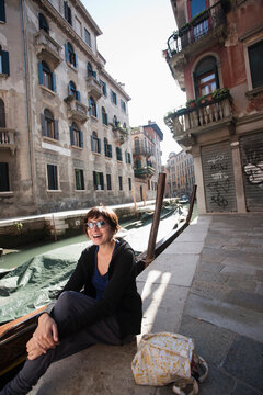 A woman sitting next to a canal in Venice, Italy.
