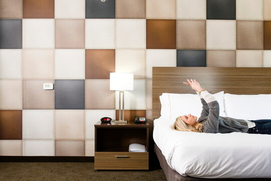 A Beautiful Lady Takes Selfie As She Lies On A Motel Room Bed.