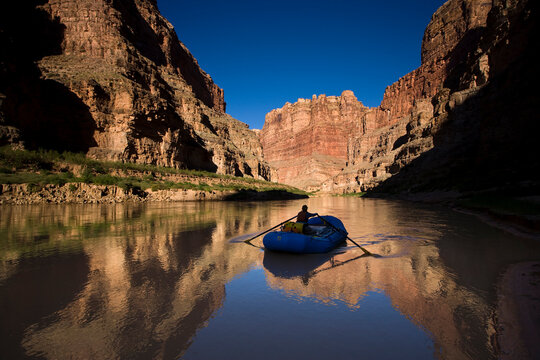 A person rowing an inflatable raft down the Colorado river, Utah.