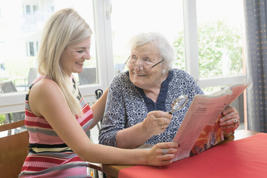 Senior woman reading newspaper with her daughter