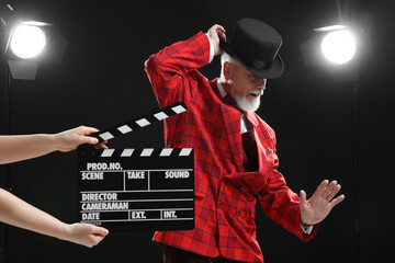 Senior actor performing role while second assistant camera holding clapperboard on stage. Film industry