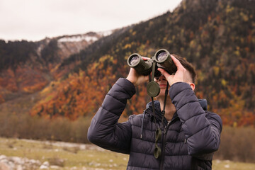 Boy looking through binoculars in beautiful mountains