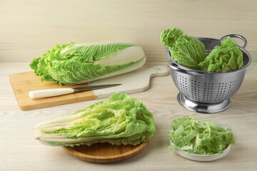 Whole and cut fresh ripe Chinese cabbages on white wooden table