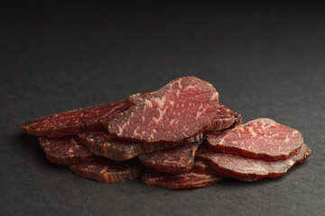 Pieces of delicious beef jerky on dark table, closeup