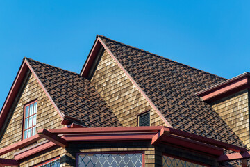 Double gable style roof tops with visible window and dark brown brick with cement roof tiles and gazebo foreground