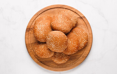 Fresh buns with sesame seeds on white marble table, top view