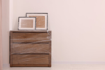 Picture frames and chest of drawers wrapped in stretch film indoors