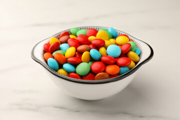 Bowl with tasty colorful candies on white marble table, closeup