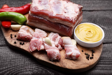 Pieces of pork fatback with chilli pepper and sauce on wooden table, closeup