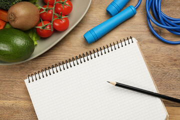 Weight loss concept. Notebook, skipping rope and different products on wooden table, flat lay