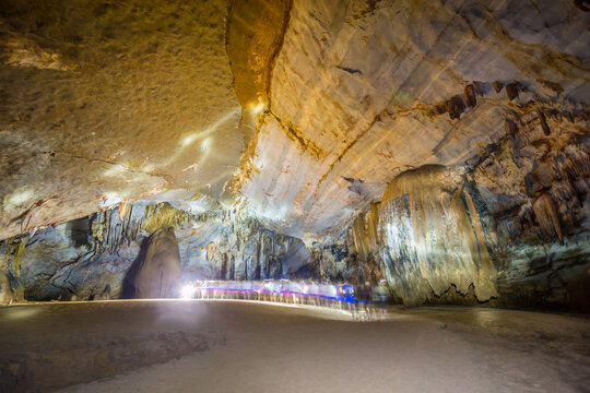Inside a large cave lit by a  headlamps of a line of people walking through, Phong Nha in Vietnam