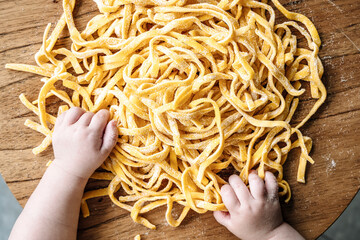Pasta and child. Baby cooks Italian fresh pasta in the home kitchen. Food and kids concept.
