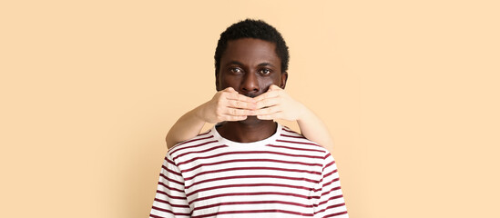 Person covering mouth of African-American man on beige background. Stop racism