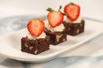 Deliciously rich cake brownie slice with Chantilly cream and fresh strawberry.