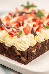 Deliciously rich cake brownie slice with Chantilly cream and fresh strawberry.
