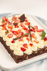 Deliciously rich cake brownie slice with Chantilly cream and fresh strawberry.