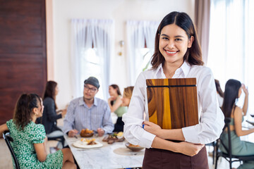 Portrait of Asian woman waiter stand and look at camera in restaurant. 