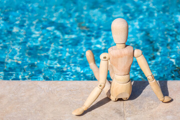 Wooden mannequin near swimming pool, closeup