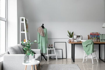 Interior of light atelier with tailor's workplace, mannequin and sofa