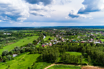 Fototapeta na wymiar Panoramic aerial view of a rural landscape with green fields, a flowing river and a village