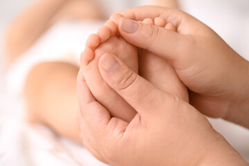 Obraz na płótnie Canvas Mother massaging her baby's feet in bedroom, closeup