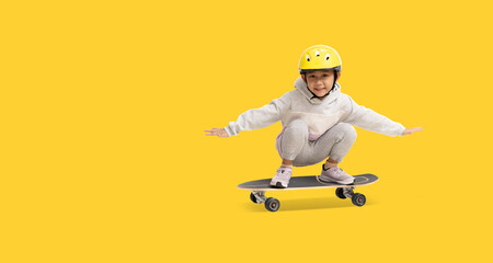 Happy asian little girl playing skateboard wearing a helmet, Full body portrait isolate on yellow background with clipping path for design work © kromkrathog