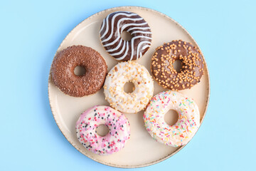 Plate of sweet donuts on color background