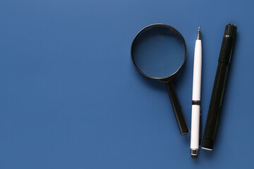 Pen, marker and magnifier on color background