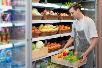 American man grocery working in supermarket with fruit and vegetable background