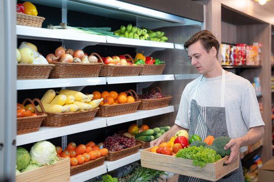 American man grocery working in supermarket with fruit and vegetable background